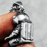 A detailed silver astronaut pendant featuring a space suit and backpack, designed for jewelry or collectibles.