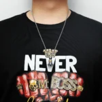 Close-up of a person wearing a silver chain with a pendant featuring a skull and the words "Never Boss" in bold letters, displayed against a black T-shirt.