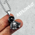 Silver astronaut pendant necklace with a black spherical head, hanging from a chain, perfect for space enthusiasts and science lovers.