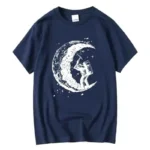 A astronaut figure standing on a crescent moon with a telescope, printed on a navy blue T-shirt.