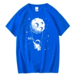 Bright blue T-shirt featuring a whimsical illustration of a moon with a smiling face and a small astronaut holding a string attached to the moon, set against a starry space background.