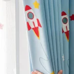 Colorful rocket ship and star appliqué on light blue fabric, perfect for a child's bedroom or playroom.