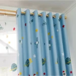 Bright blue curtain featuring planets, stars, and rockets, perfect for a child's space-themed room decor. Made from lightweight fabric with metal grommets for easy hanging.