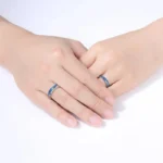 Two hands with matching blue science-themed rings, gently touching each other.