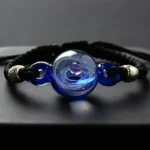 Elegant black cord bracelet featuring a central blue glass bead with swirling patterns and metallic accents, perfect for science-inspired jewelry enthusiasts.