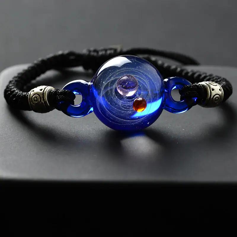 Blue glass planetary bracelet with cosmic design and metallic accents.