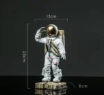 A detailed astronaut figurine with a gold helmet, measuring 23cm tall and 13cm wide, standing on a textured base. Perfect for science-themed decor or educational displays.