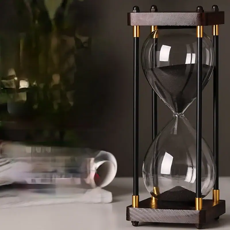 Sand Timer - Elegant Glass Hourglass for Time Measurement Stylish glass hourglass timer with black sand, featuring a wooden and metal frame, ideal for educational and decorative purposes.