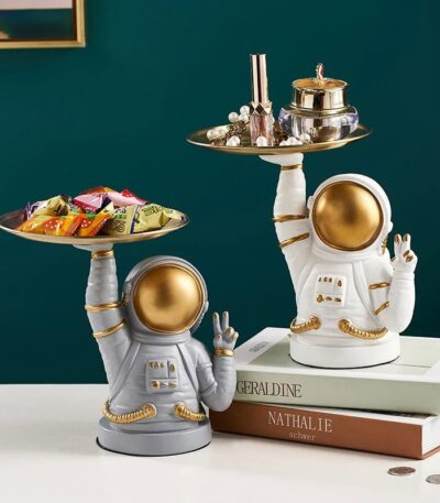 Astronaut figurines with gold accents holding trays of candies and jewelry, perfect for science decor and educational toys.