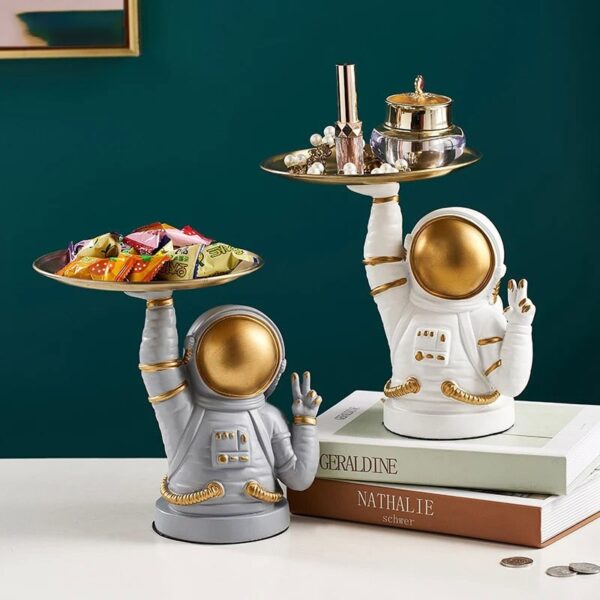 Astronaut figurines with gold accents holding trays of candies and jewelry, perfect for science decor and educational toys.