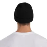 Close-up of a person wearing a plain black knit beanie hat, viewed from behind, on a white background.