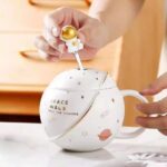 Space-themed ceramic mug with lid and spoon featuring planets, stars, and galaxy designs, perfect for science lovers and space enthusiasts.