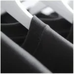Close-up of black T-shirts hanging on white hangers, showcasing fabric texture and clothing display.
