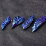 Four striking blue crystal mineral specimens with iridescent surfaces displayed on a dark background, showcasing their natural beauty and intricate crystal formations.