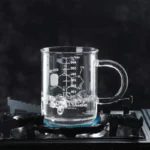 Glass beaker filled with boiling water on a stove burner, demonstrating basic chemistry lab equipment and heat application.