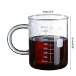 Clear glass beaker filled with red liquid, marked with measurement lines, on a white background.