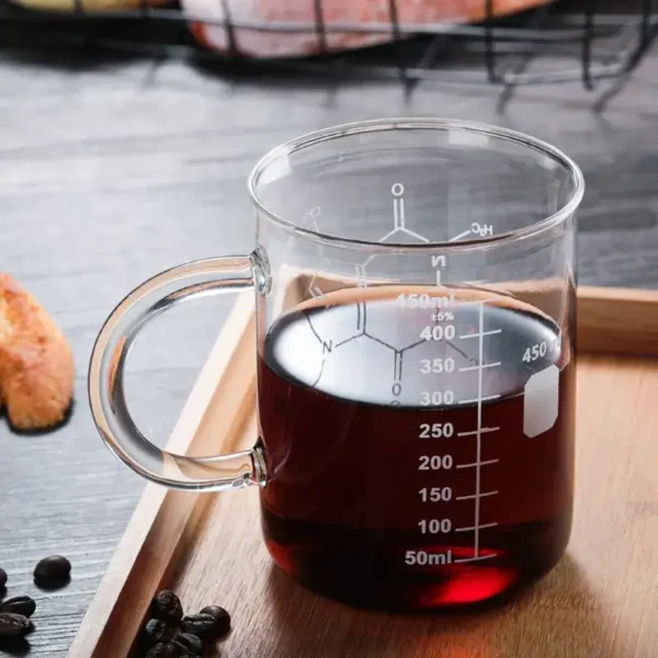 Beaker with dark liquid for science experiments, transparent glass with measurement markings, placed on a wooden surface.