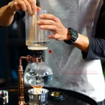 A person conducting a science experiment with a glass apparatus and water, demonstrating scientific principles in a hands-on educational setting.