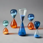 An arrangement of six vibrant glass hourglasses in various sizes and colors, showcasing their transparent and reflective surfaces, perfect for science-themed decor and educational purposes.