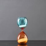Elegant glass hourglass with blue and orange sand, showcasing a classic time-measuring device for educational and decorative purposes.