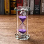 Clear glass hourglass with vibrant purple sand flowing between chambers, perfect for educational demonstrations or stylish decor.