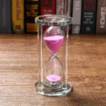 Clear glass sand timer with pink sand, measuring time for science experiments and educational activities.