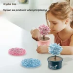 Young girl observing a pink crystal tree in a pot, with additional blue and pink crystal trees on the table, demonstrating crystal formation.