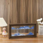 Decorative miniature mountain scene in a wooden frame with blue and white peaks.