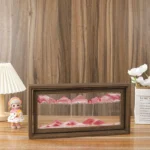 A miniature magnetic mountain landscape with pink peaks inside a wooden frame.