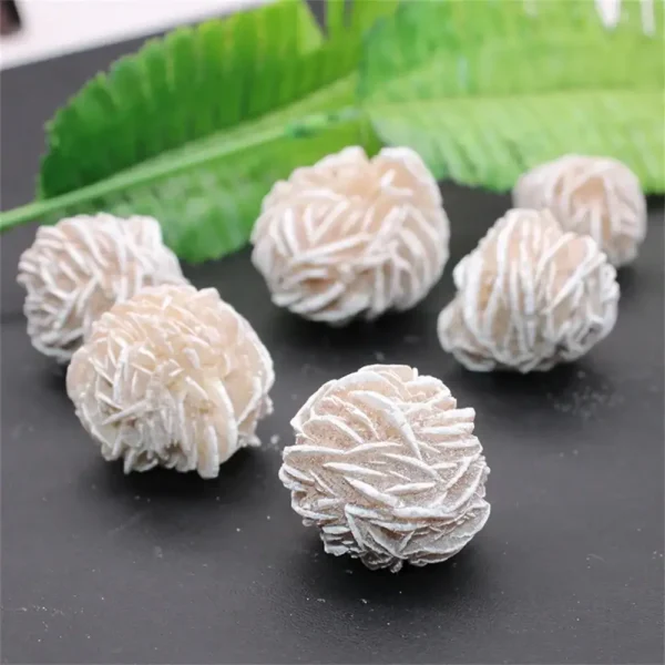 Close-up of white truffle confections with textured surface, arranged on a dark background with green leaves for contrast. Perfect for dessert lovers and gourmet food enthusiasts.