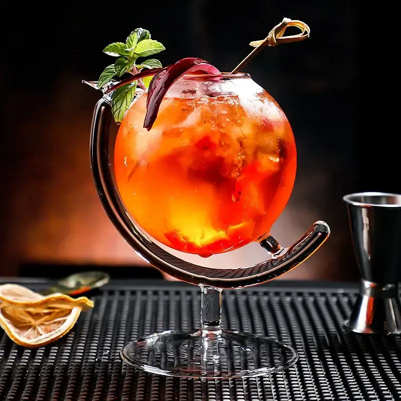 Tropical Cocktail in Glass with Fruit Garnish A vibrant tropical cocktail served in a glass with a metal stand, garnished with a mint sprig and a slice of fruit, perfect for a refreshing summer drink.