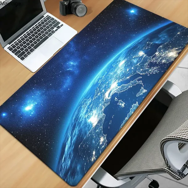 A space-themed desk mat featuring a detailed image of Earth from space, with stars and cosmic background, placed on a wooden desk alongside a laptop and camera.
