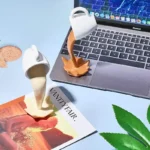Miniature coffee pot and cup desk decor with flowing liquid effect, placed on a laptop and magazine, ideal for science-themed decor and educational toy displays.