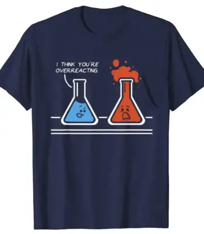 A humorous graphic T-shirt featuring two cartoon laboratory flasks with faces, one blue and one red, with the blue flask saying "I think you're overreacting" as the red flask bubbles over.