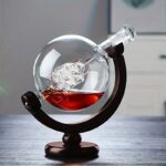 Elegant glass globe with a black stand, containing a chemical flask with red liquid and a glass sculpture inside, showcasing a scientific theme.