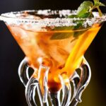 Vibrant cocktail served in a glass with tentacle-shaped ice cubes and fresh mint garnish, creating a visually striking and fun presentation perfect for themed parties or science-inspired decor.