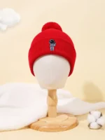 Bright red knit beanie hat featuring a small astronaut patch, perfect for cold weather and space enthusiasts.