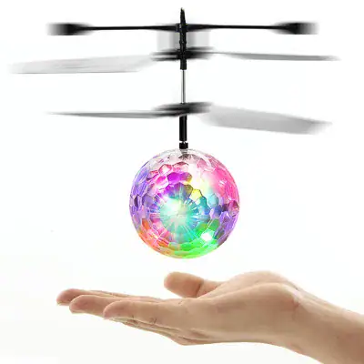 Small helicopter toy with a colorful, glowing LED-lit ball attached, hovering above a person's hand, demonstrating a fun science gadget.