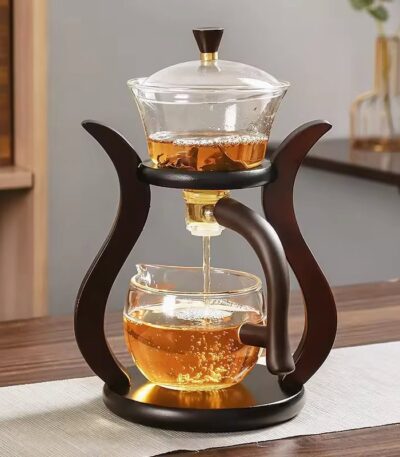 Elegant glass teapot with infuser and wooden stand, perfect for brewing and serving tea with a modern, stylish design.