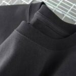 Black crewneck sweatshirt on a hanger, close-up view.