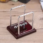 Magnetic Newton's Cradle educational toy with metal balls and wooden base for science experiments and decor.
