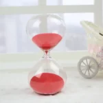 Sand timer with red sand, perfect for time management and educational activities. Clear glass design with a modern aesthetic, ideal for classrooms, offices, or home decor.