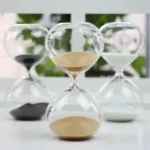 Sand timer with black and white sand in glass hourglass, ideal for science decor and educational purposes.