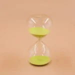 Elegant transparent hourglass with green sand, perfect for science demonstrations, home decor, or as an educational toy to teach time measurement.