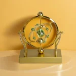 A decorative atom model with metallic spheres representing electrons and nucleus, mounted on a gold-colored stand, ideal for science-themed decor or educational purposes.