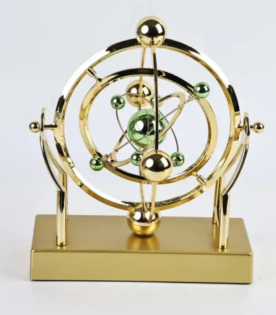 Atomic model desk decor with gold and green spheres representing electrons and nucleus, mounted on a rectangular gold base. Perfect for science enthusiasts and educational settings.