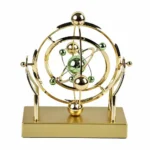 A decorative atomic model with gold and green metallic spheres representing electrons and protons, mounted on a gold base, ideal for science enthusiasts and educational settings.