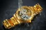 Luxurious gold skeleton watch with visible gears and mechanical movement, water splashing around it, showcasing intricate craftsmanship and elegant design.