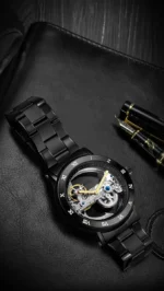 Elegant skeleton mechanical watch showcasing intricate gears and movement, placed on a black leather surface with a pen nearby.