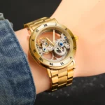 Elegant gold skeleton wristwatch with visible internal gears and Roman numeral markers, worn on a person's wrist.